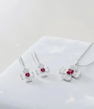 Red stone pendant set with a silver color flower motif necklace and hook earrings for artificial jewellery online shopping in Lahore.